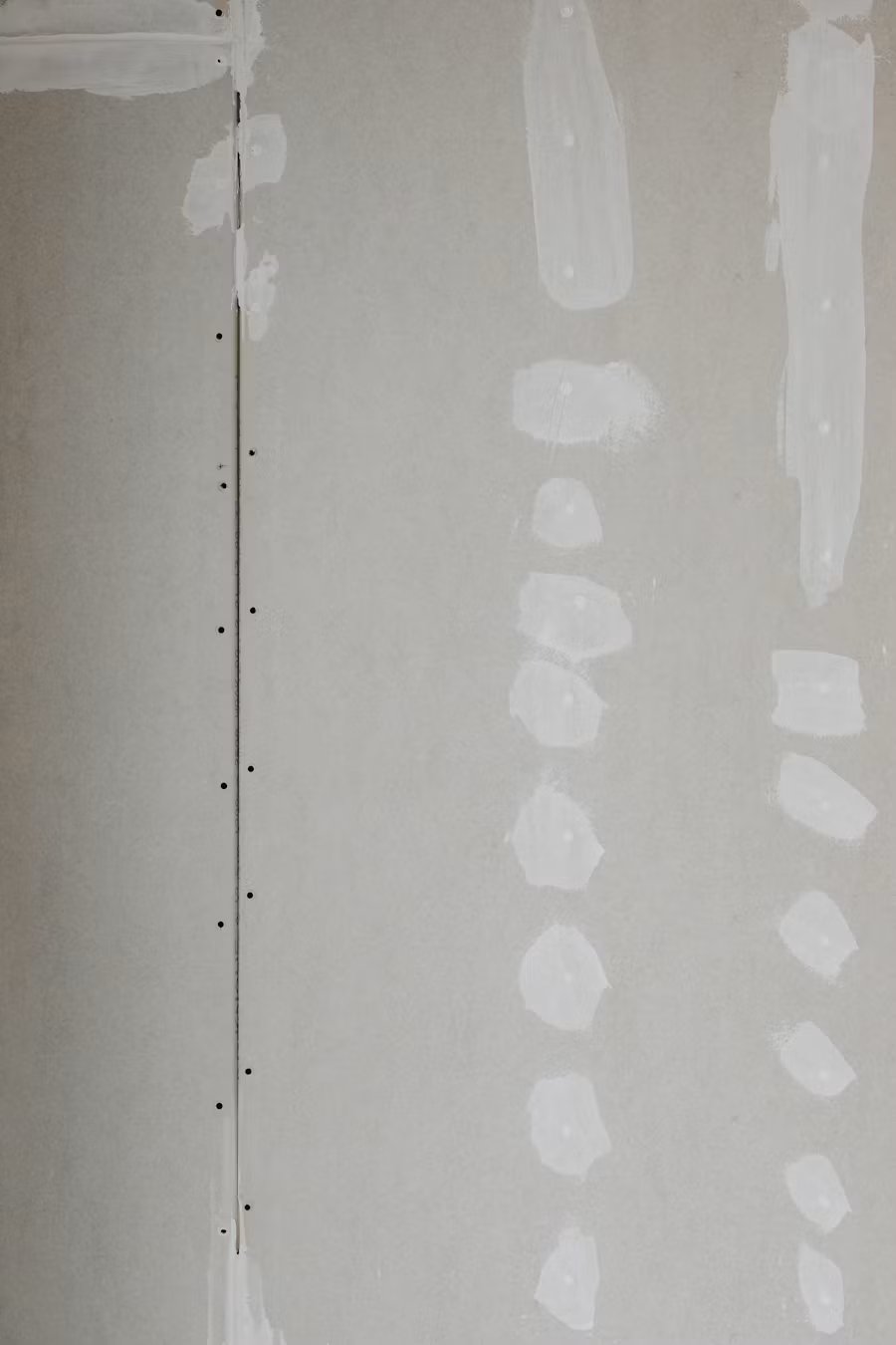 Drywall with spackling patches and fastener holes along vertical seam