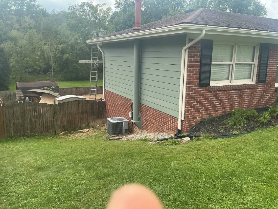 Brick and vinyl sided house with HVAC unit and ladder against exterior wall