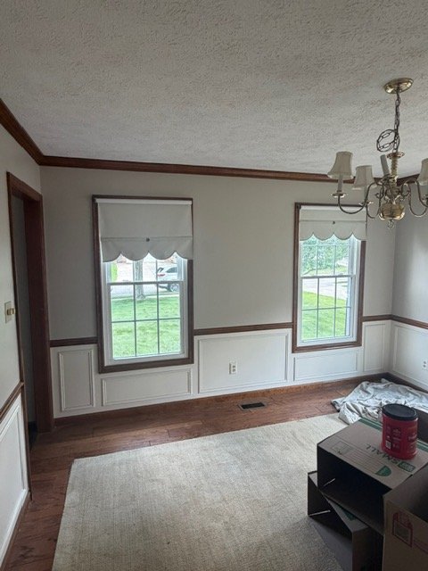 Empty room with dark wood trim, two windows, hardwood floors, and ceiling fixture