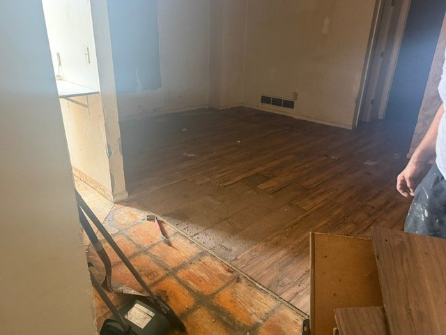 Empty room with hardwood flooring and white walls during renovation