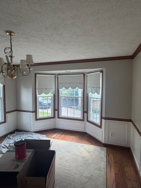 Bright sunroom with triple patio doors, wood beams, wainscoting, and hardwood flooring